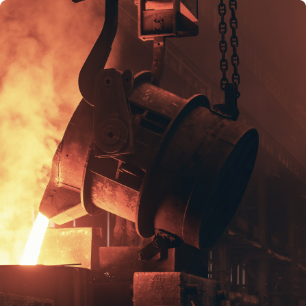 Molten aluminum being poured from a large crucible in a foundry